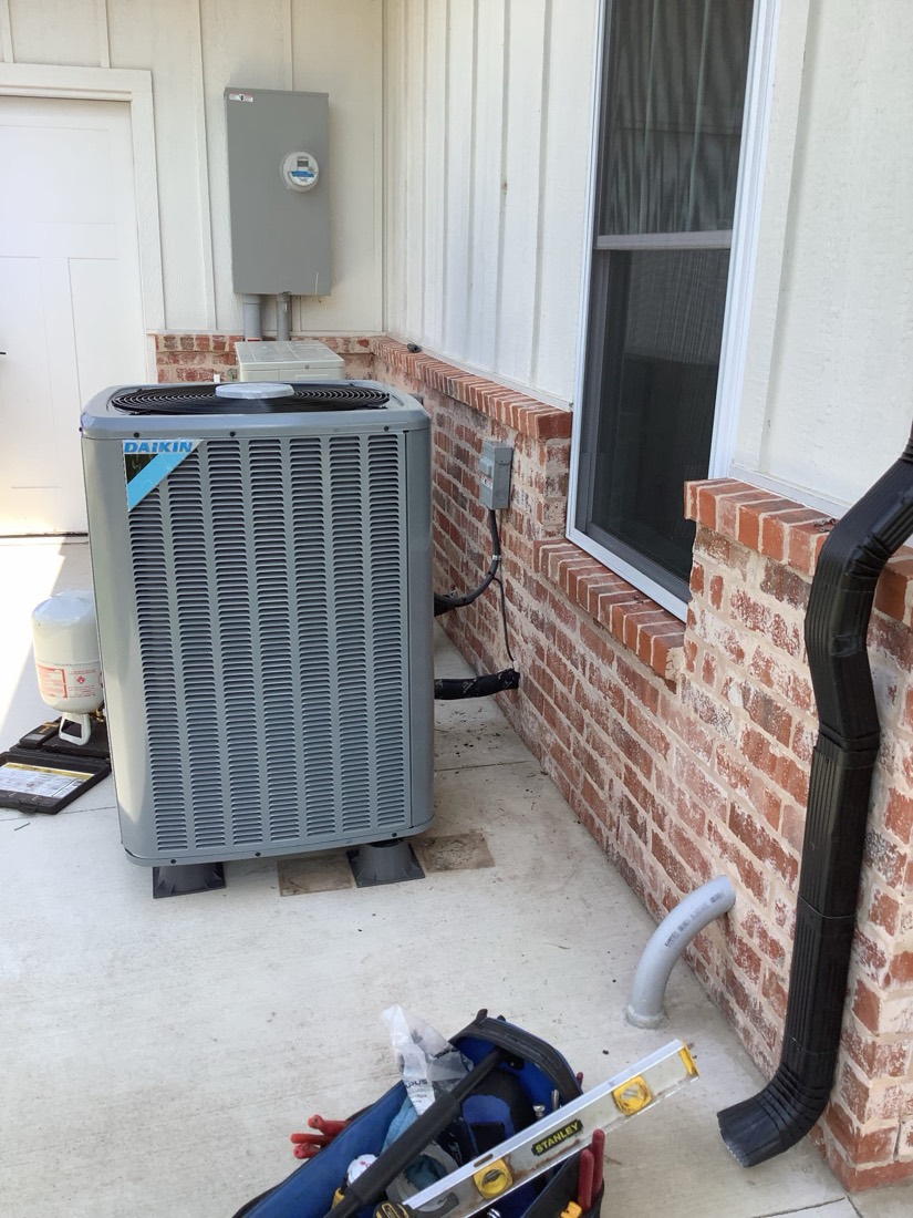 Newly installed Daikin air conditioning condenser unit in brick enclosure.
