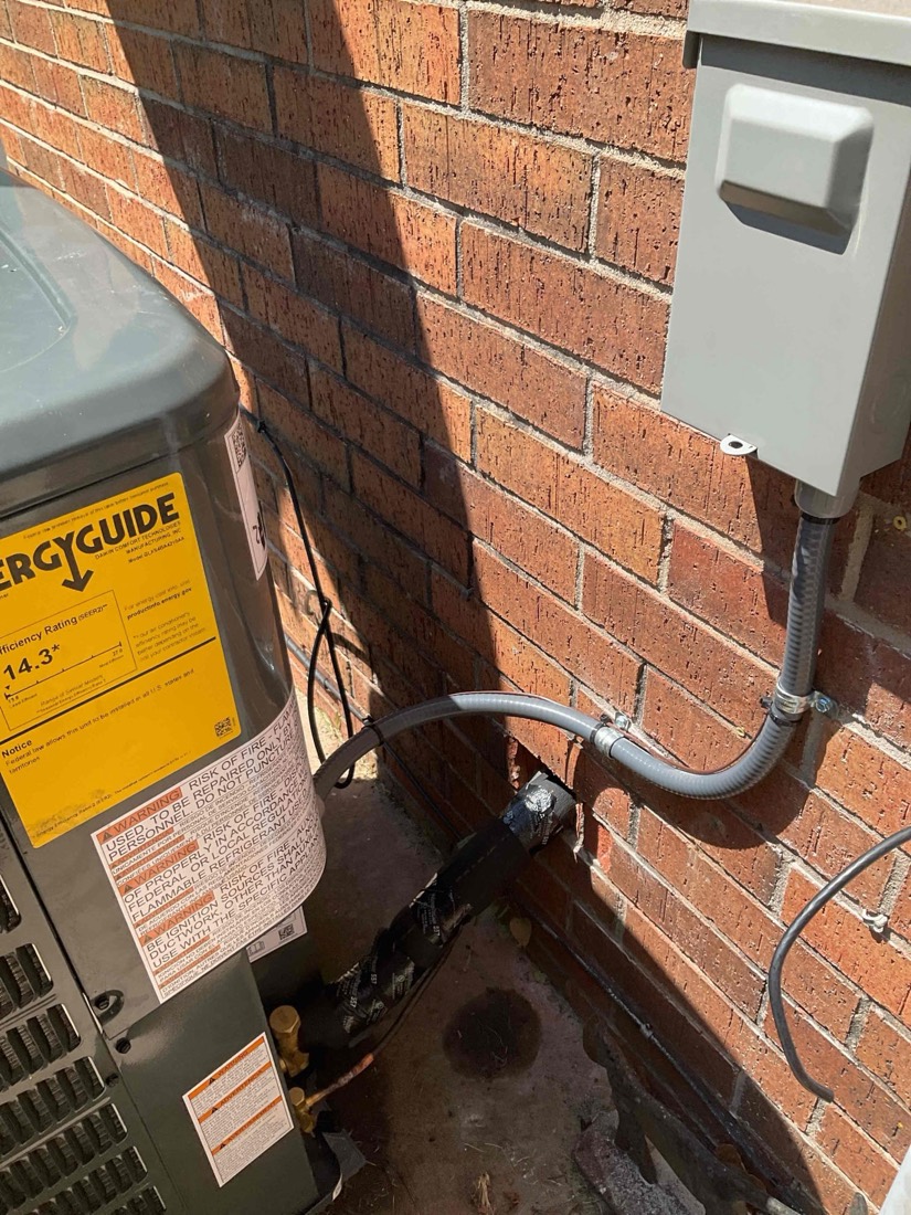 Outdoor HVAC condensing unit installed on brick.