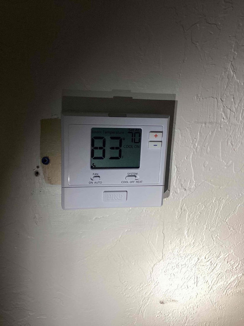 Digital programmable thermostat displaying temperature on white wall