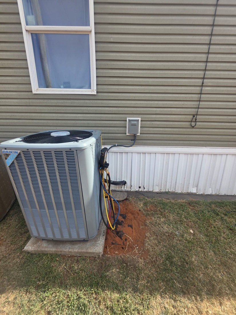 AC condenser unit on concrete pad with service lines and disconnect box against home siding.