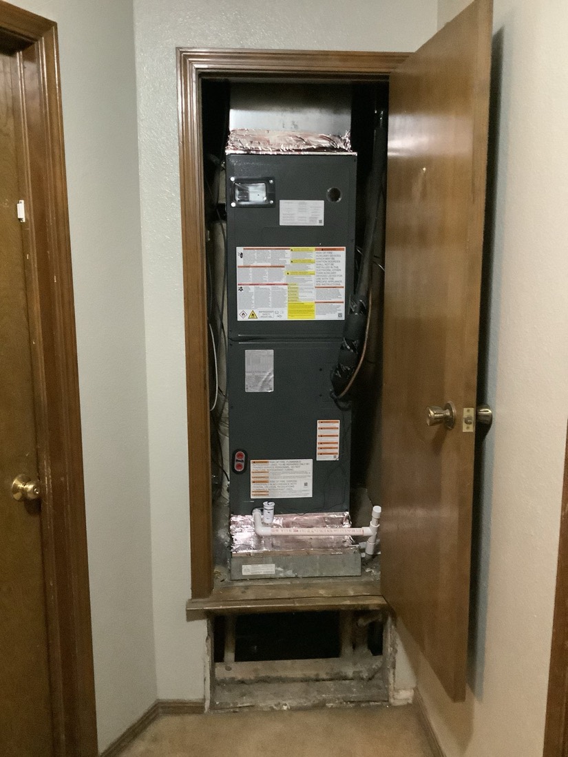 New furnace unit installed in residential utility closet with ductwork and piping connections