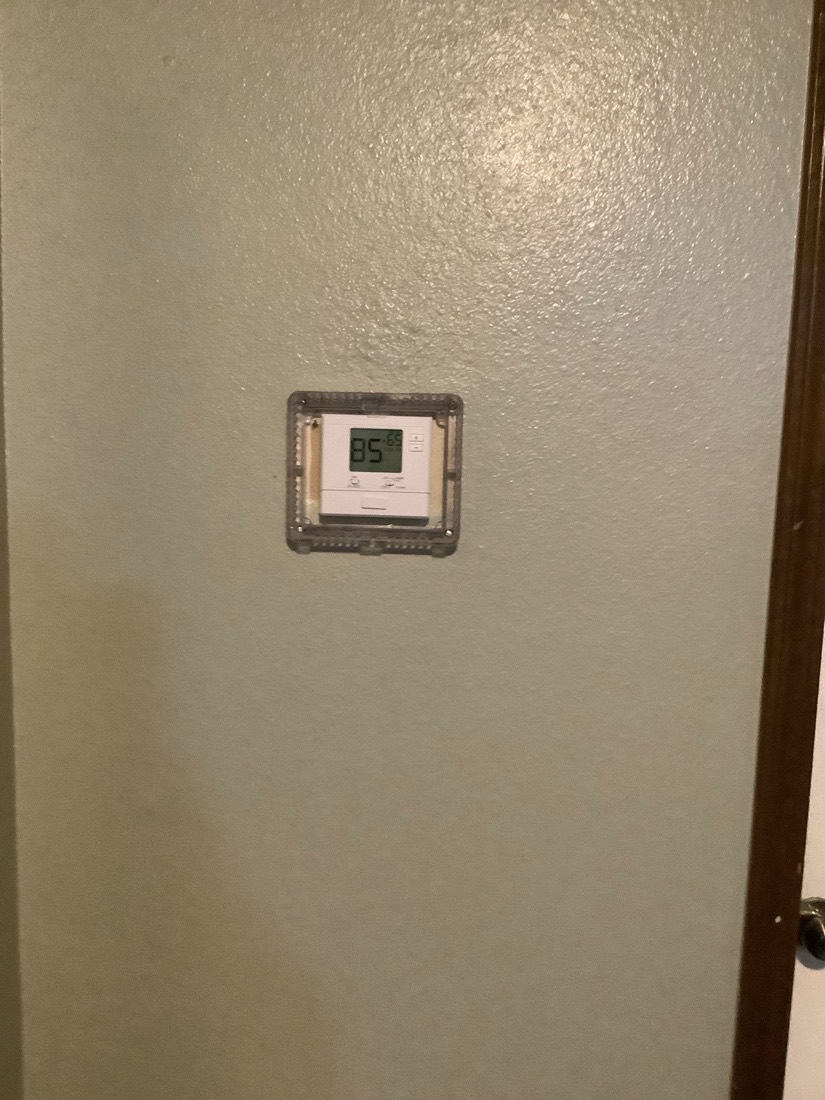 Digital programmable thermostat mounted on wall displaying temperature setting