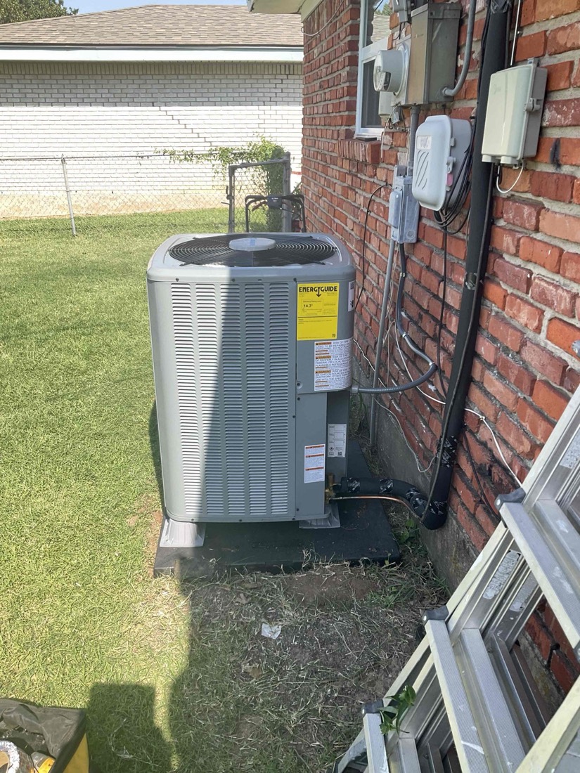 Exterior AC unit mounted against brick wall with new electrical connections