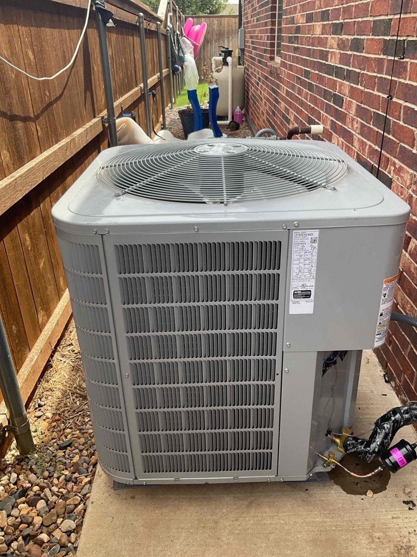 Newly installed outdoor AC condenser unit mounted against brick home