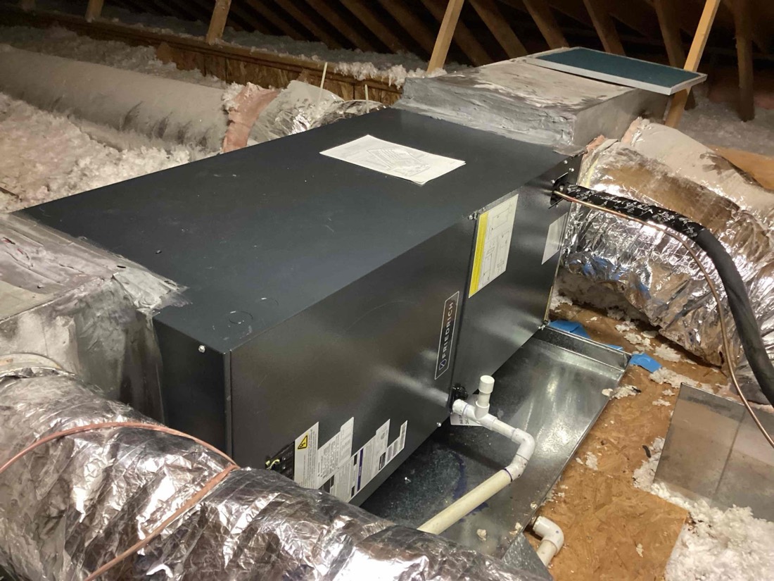HVAC auxiliary unit installed in attic with ductwork connections.