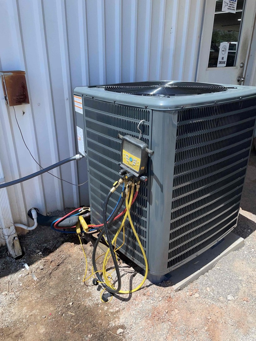 Outdoor AC unit installation with refrigerant gauges and copper lines
