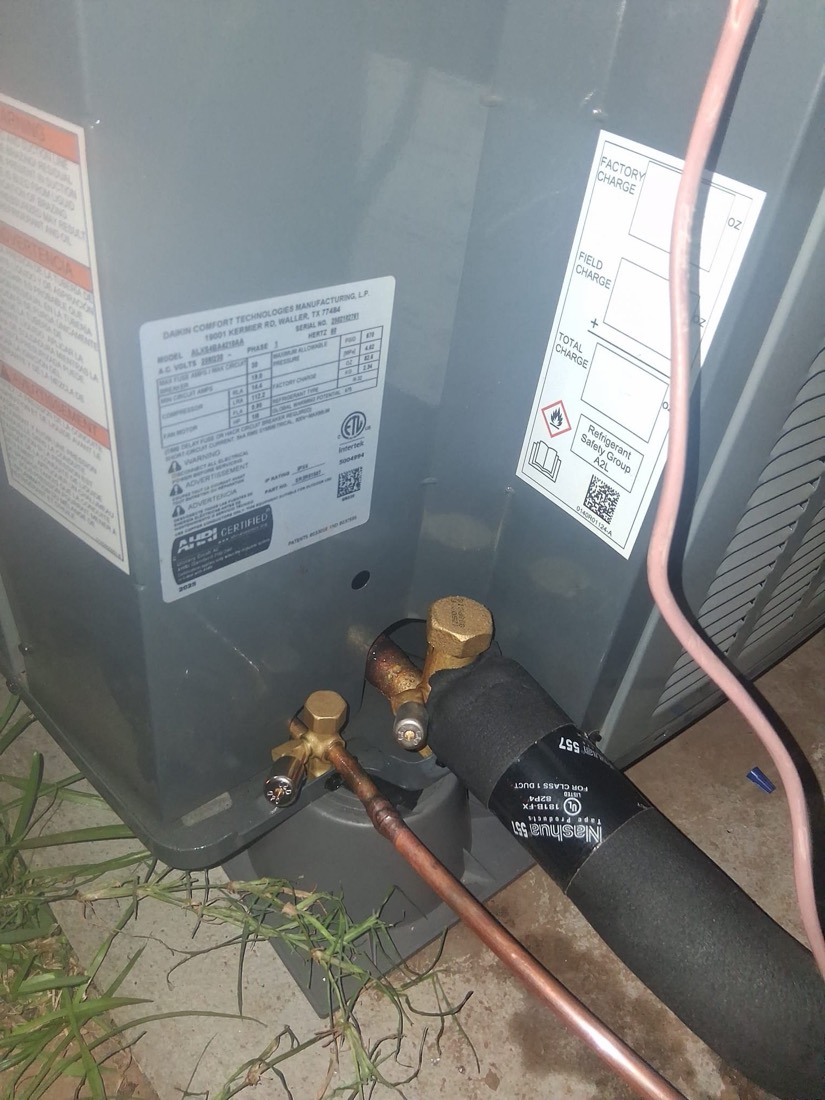 Copper refrigerant lines and brass service valves connected to outdoor AC unit