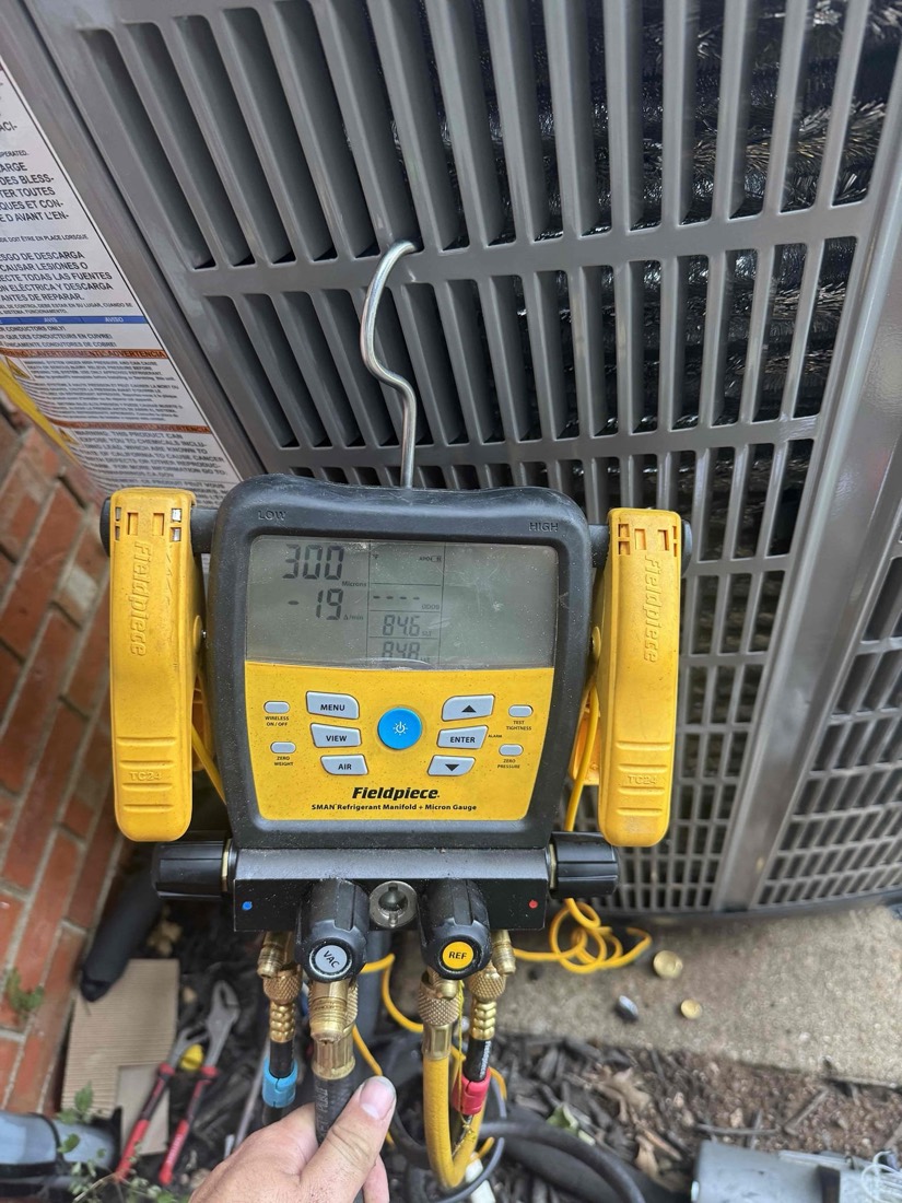 Technician holding manifold gauge for HVAC system diagnosis and refrigerant testing