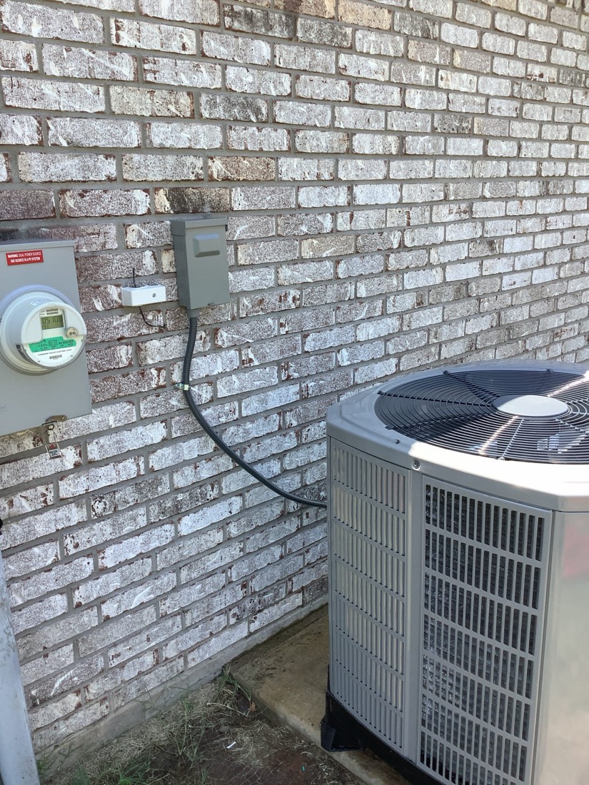AC condenser and disconnect switch on brick foundation
