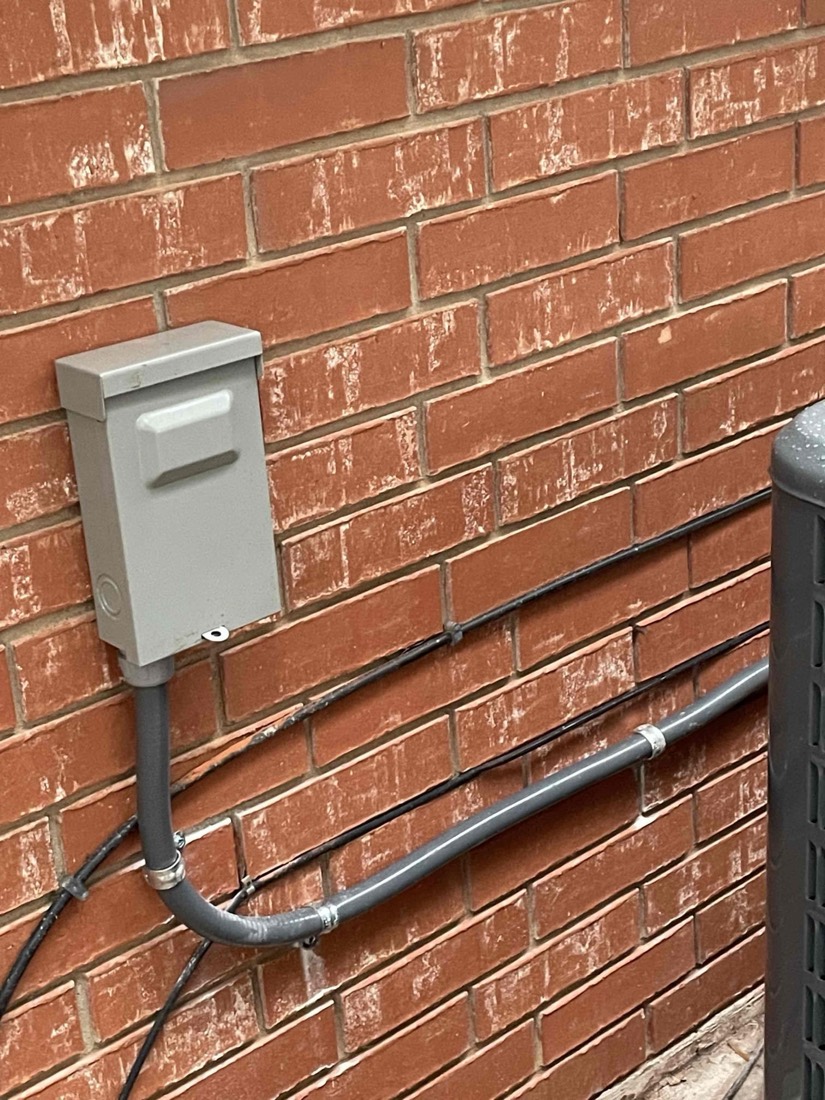 AC disconnect switch mounted on exterior wall.