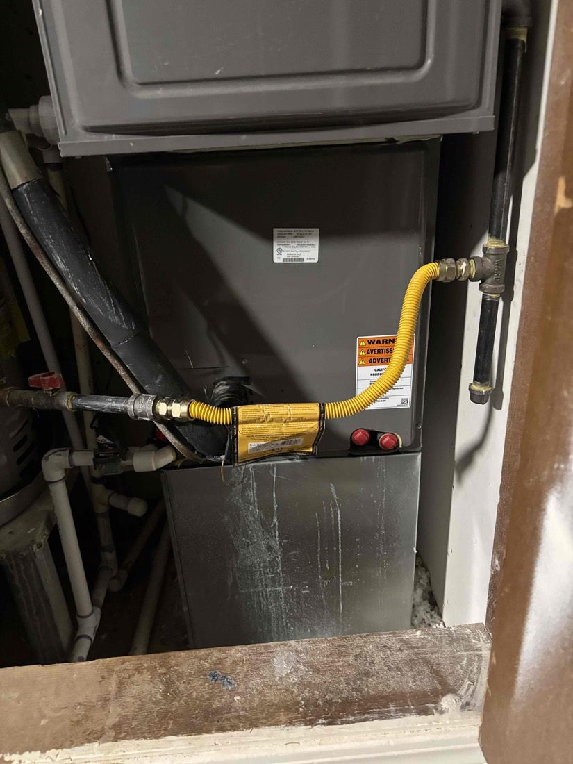 Installed furnace with yellow gas line and condensate drain connections.