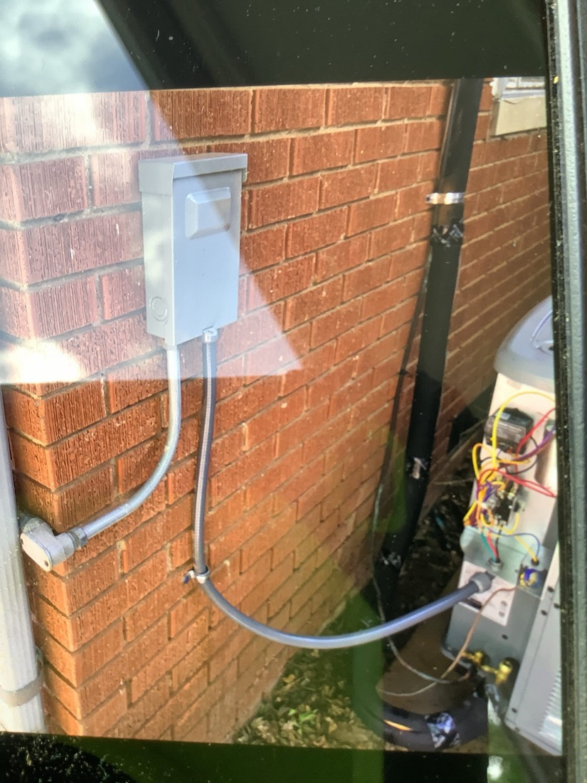 Electrical disconnect and condensate drain line on brick wall