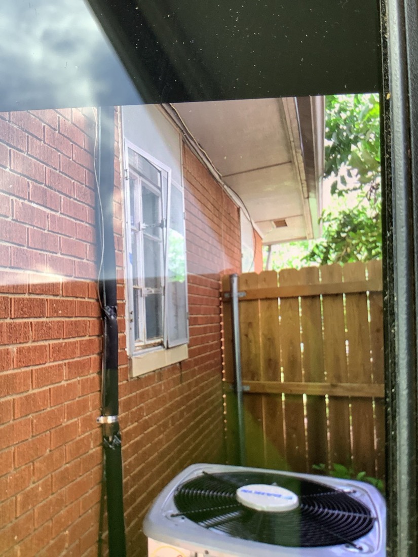 Outdoor AC condenser unit mounted on brick wall