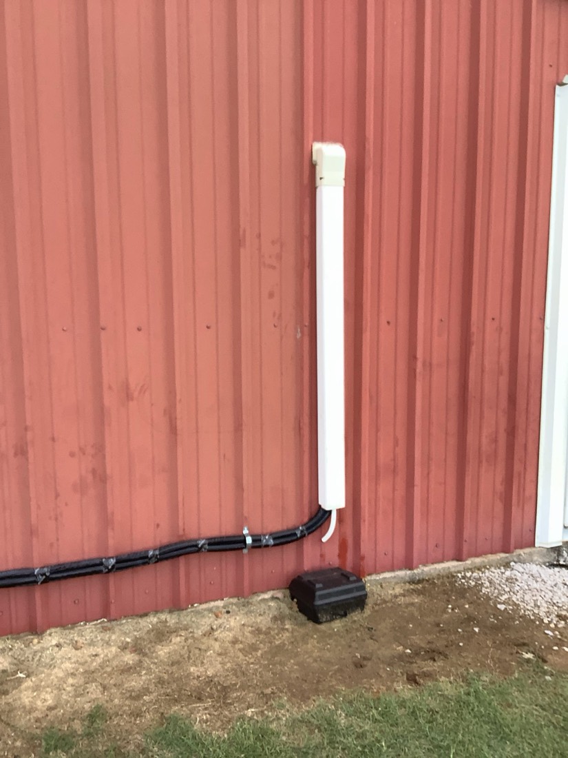 White ductwork and black refrigerant lines installed on red metal building exterior