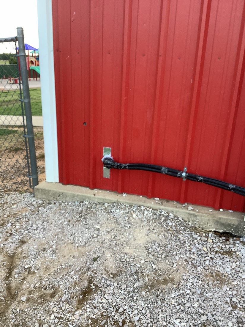 Outdoor electrical disconnect and conduit installed on red metal building wall