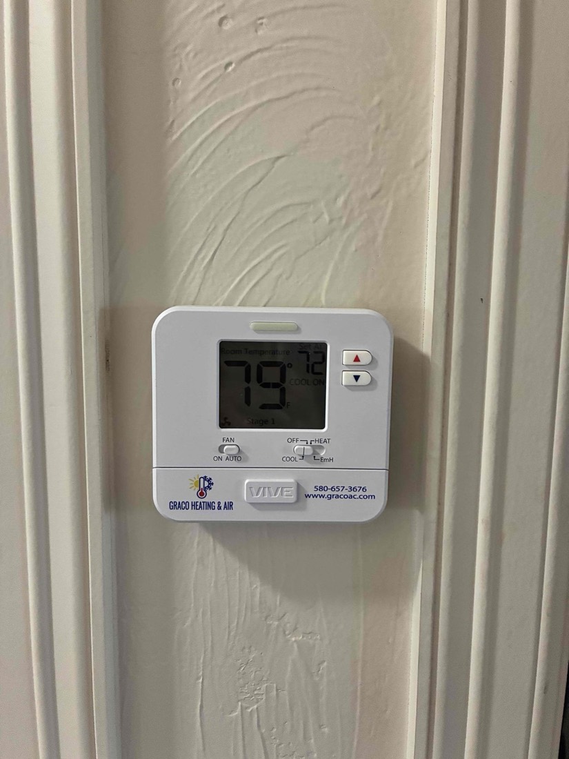 Installed digital thermostat displaying temperature reading