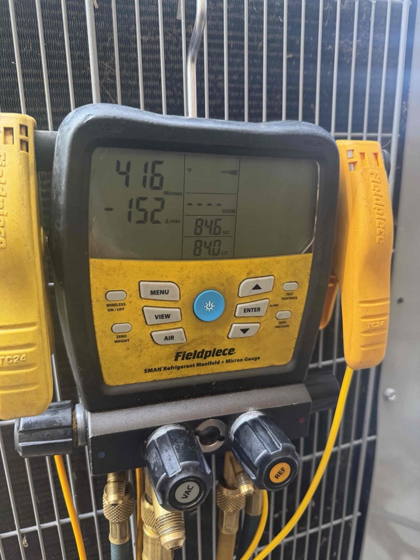 Yellow refrigerant manifold gauge showing pressure readings.