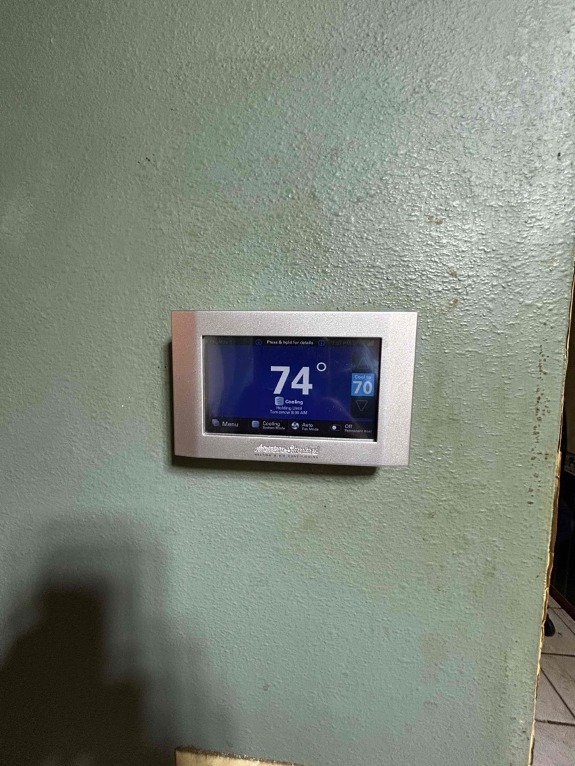 Smart thermostat displaying 74 degrees on wall.