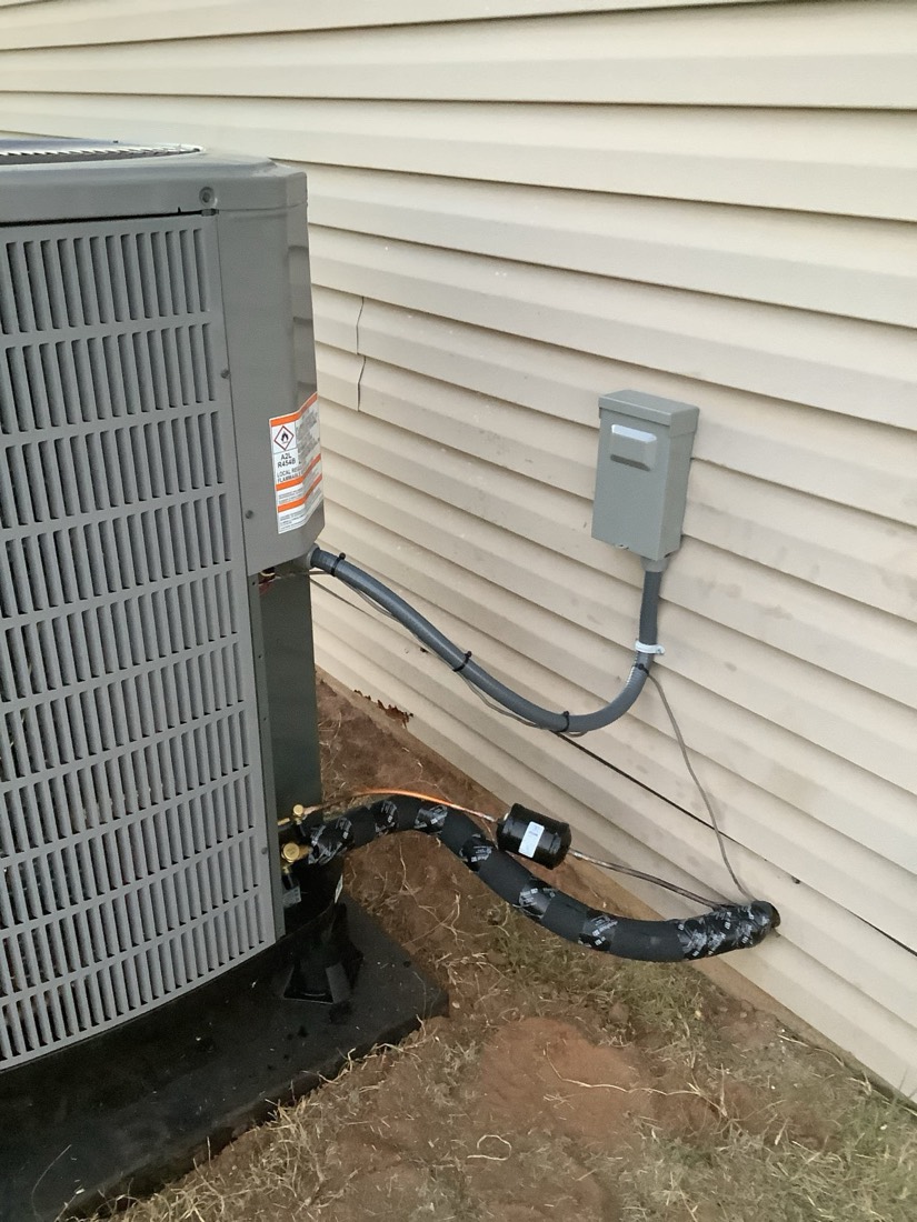 Installed AC condenser with disconnect switch and refrigerant lines