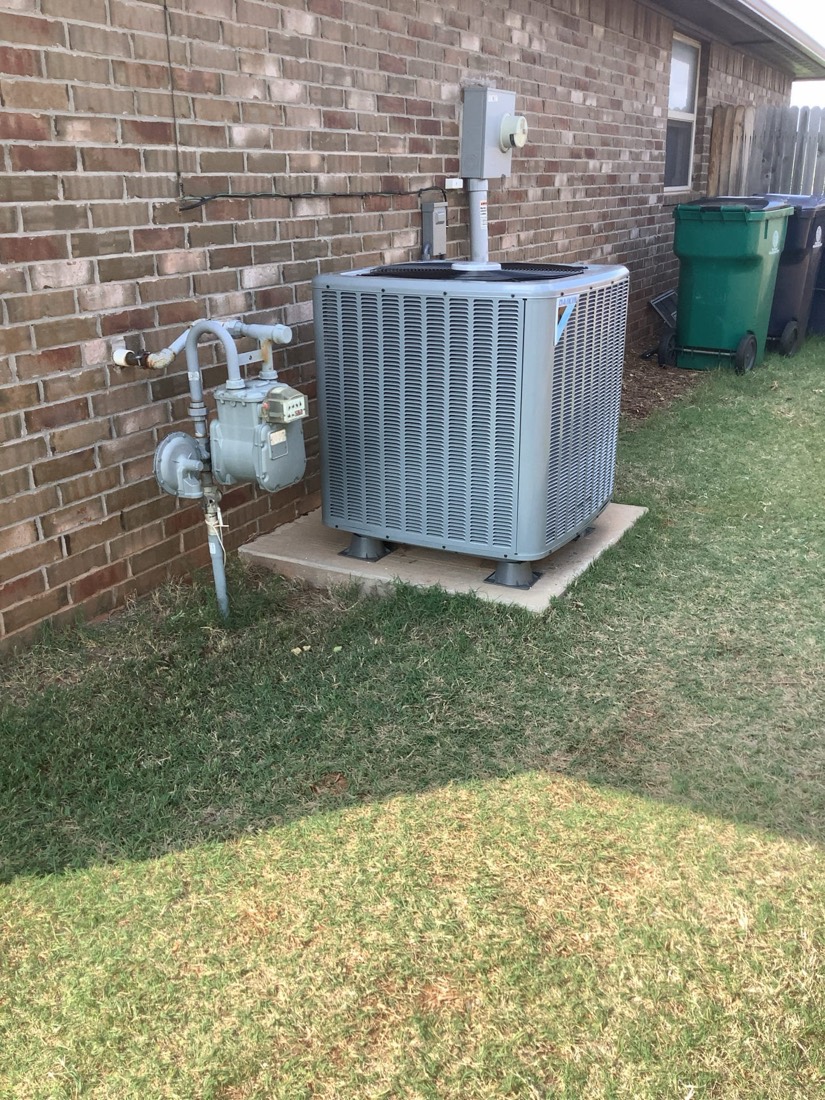Newly installed AC unit on concrete pad with refrigerant lines