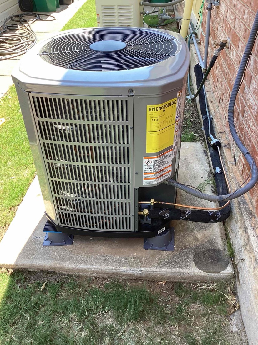 Installed AC condenser unit with refrigerant lines and power connections visible.