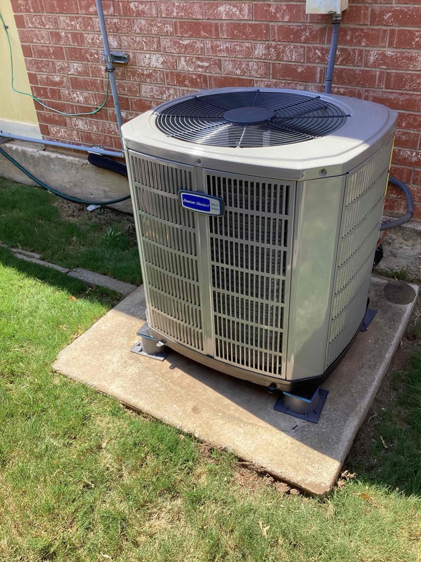Finished AC condenser installation with refrigerant lines and disconnect switch.