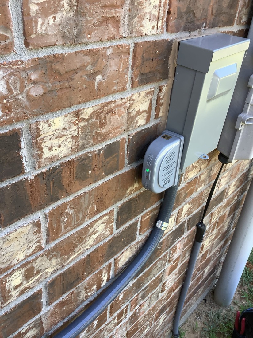 Electrical disconnect switch and junction box mounted on brick next to AC unit