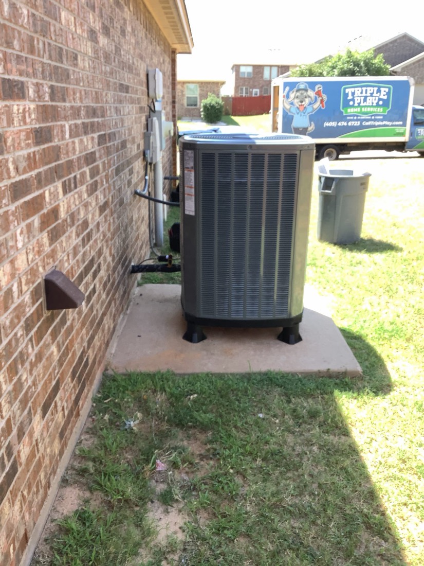 New outdoor AC condenser unit installed on concrete pad at residential home