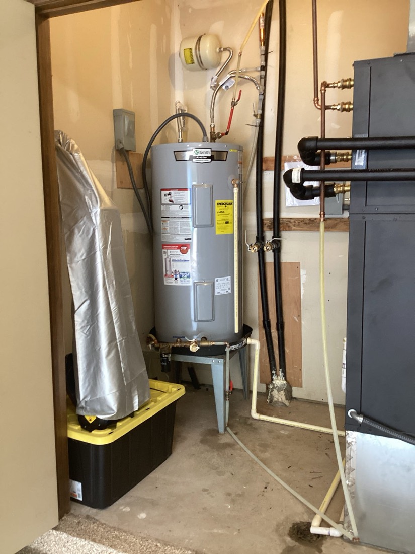 Installed water heater with drain pan, insulation, and connected plumbing lines