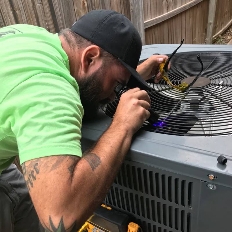 Skilled Triple Play technician servicing an HVAC system, checking wiring and components for optimal functionality and to prevent AC breakdowns and prepare your HVAC system for weather conditions.