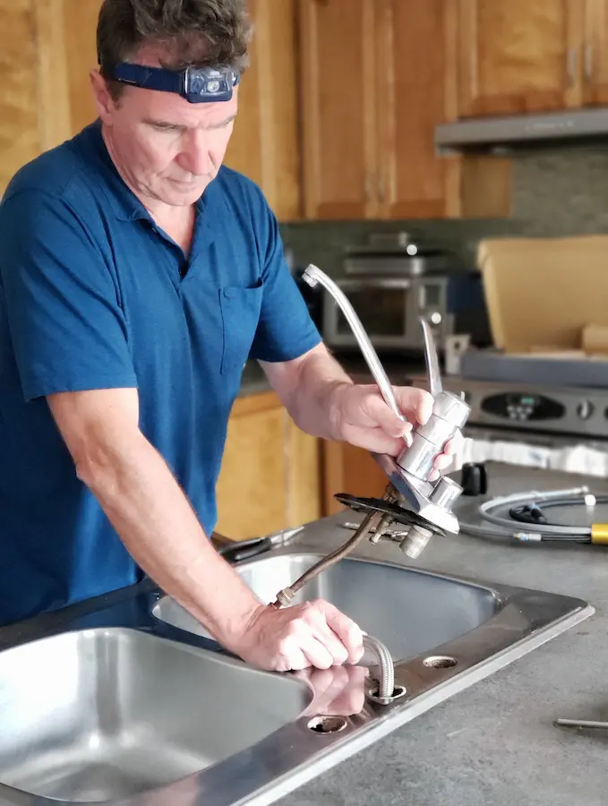 Plumber changing a kitchen faucet.
