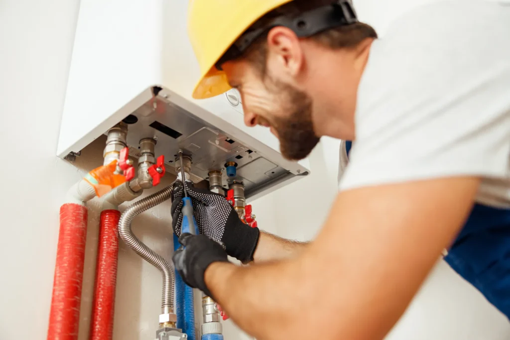 Closeup of plumber using screwdriver while fixing water heater in Village Hills, OK